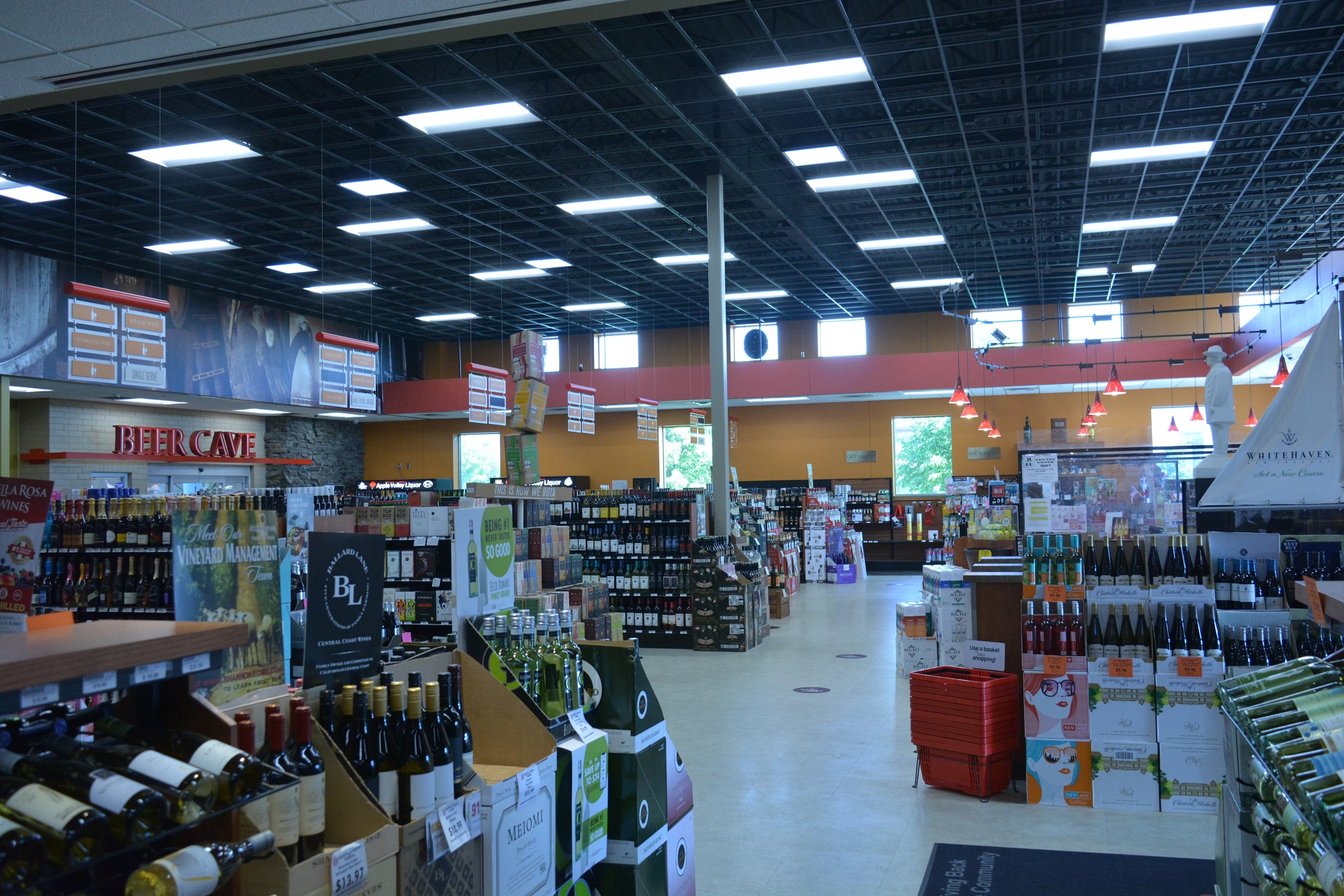 Spacious liquor store aisles with wine displays and a large refrigerated "Beer Cave" in the background.