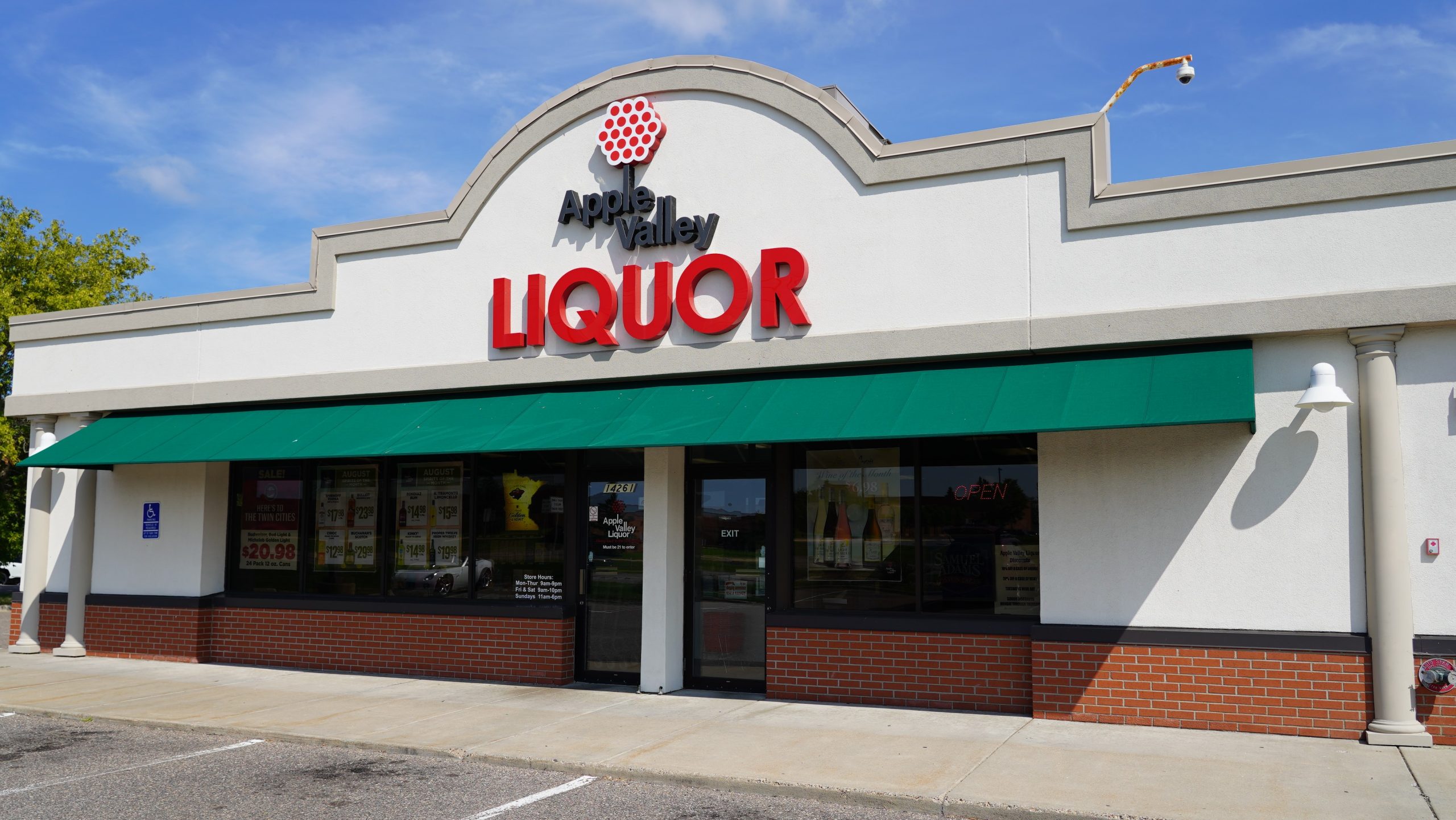 Modern Apple Valley Liquor store building with red signage, brick pillars, and a clean concrete entryway under a clear sky.