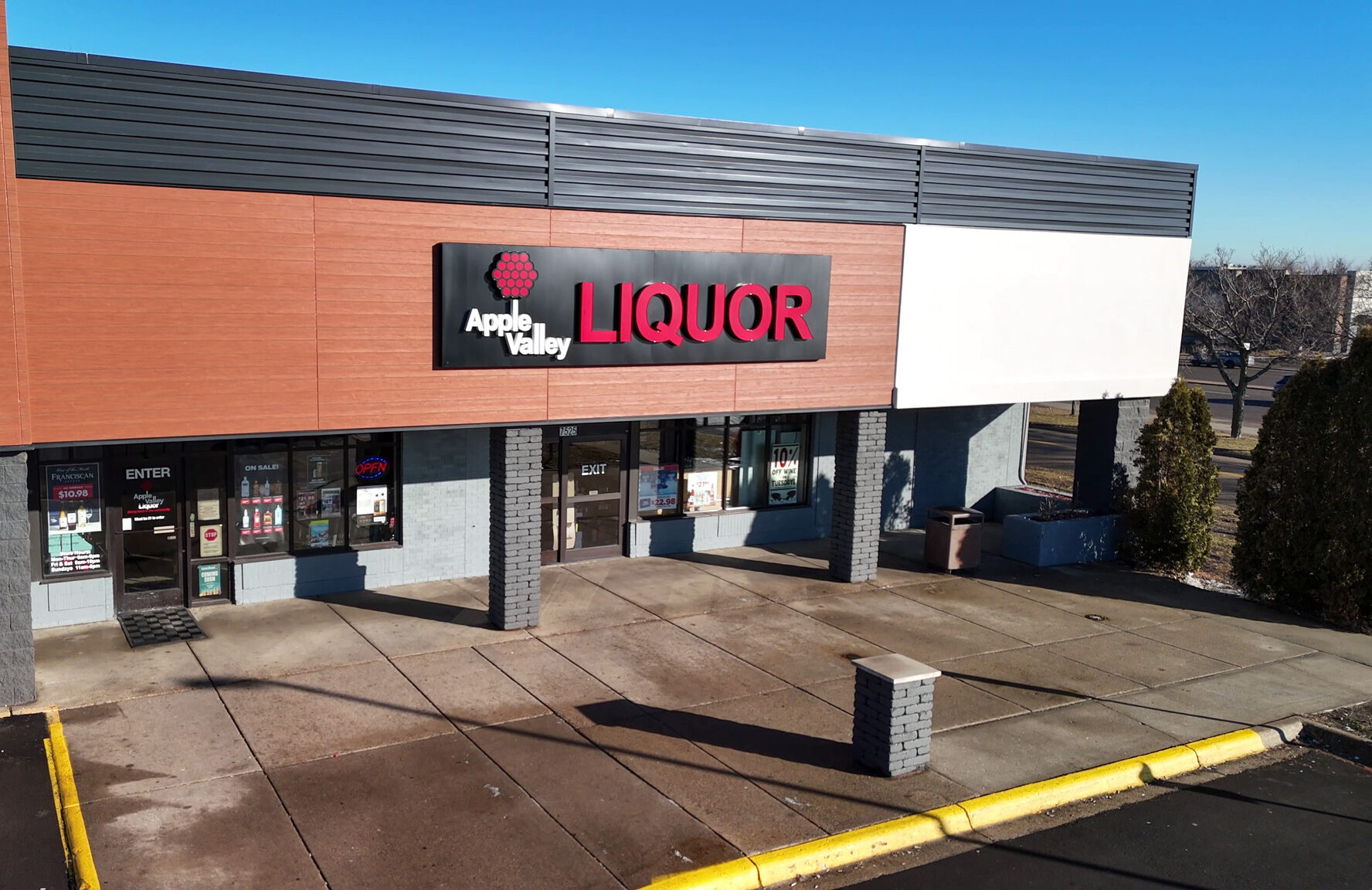 Apple Valley Liquor storefront featuring a modern wood-paneled facade and red signage on a bright sunny day.