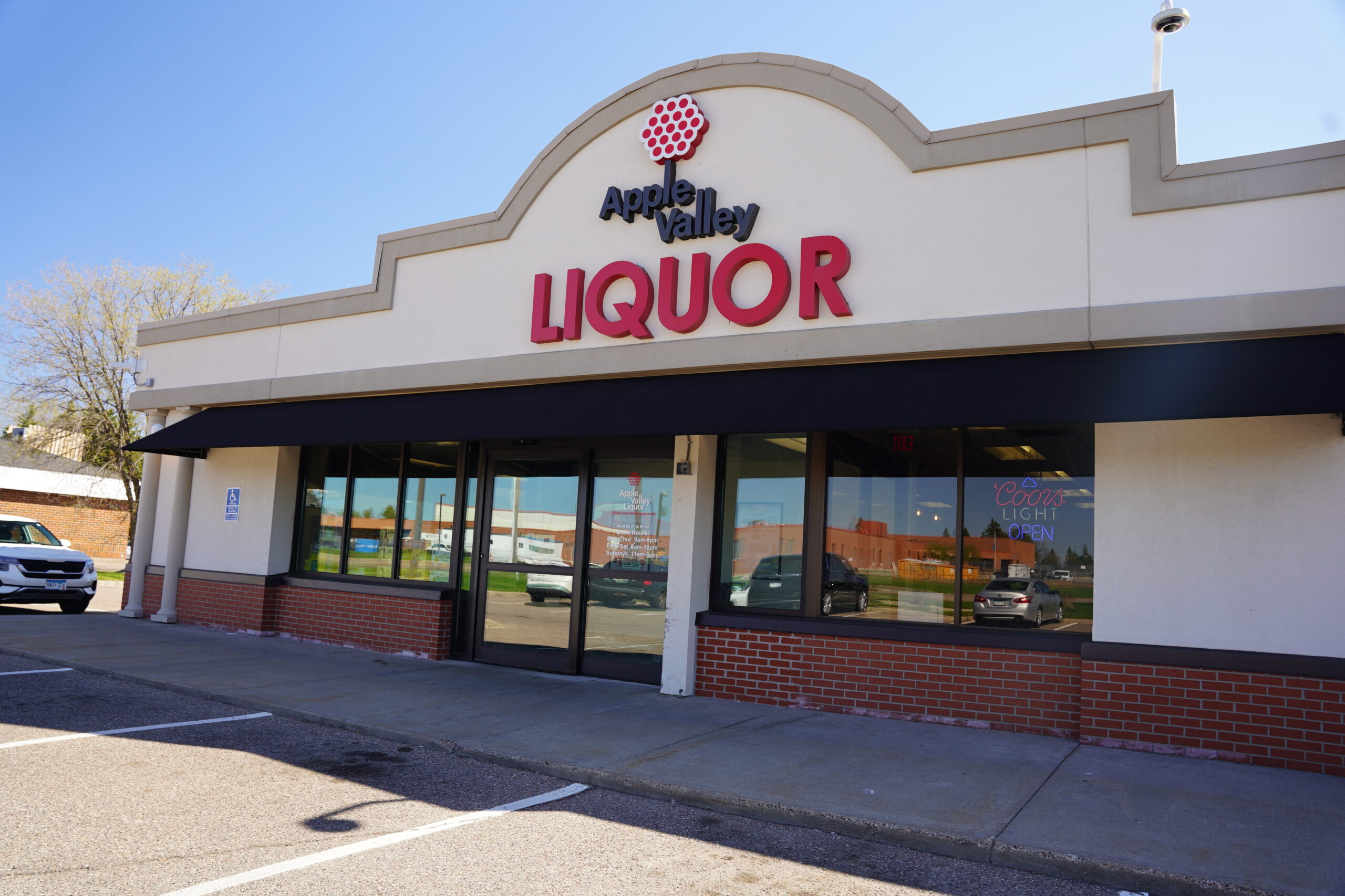 Modern Apple Valley Liquor store building with red signage, brick pillars, and a clean concrete entryway under a clear sky.
