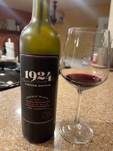 1924 wine bottle next to a wine glass with wine in it on the counter